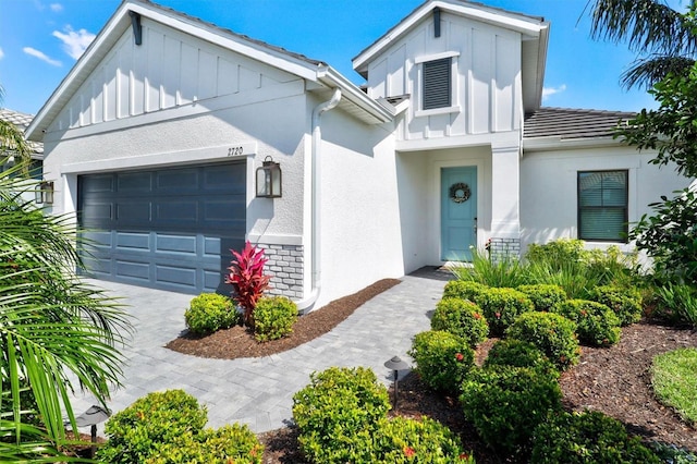 view of front facade featuring a garage, decorative driveway, board and batten siding, and stucco siding