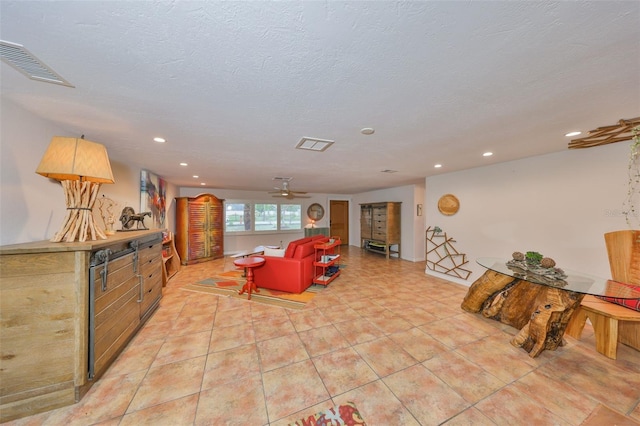 living area featuring a textured ceiling, light tile patterned floors, visible vents, and recessed lighting