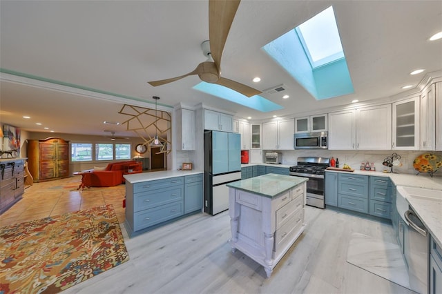 kitchen featuring a skylight, blue cabinetry, stainless steel appliances, visible vents, and white cabinets