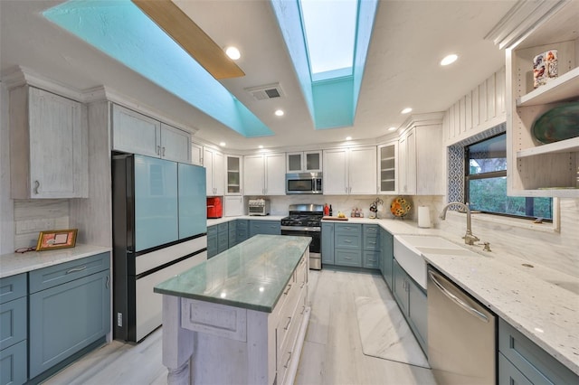 kitchen with a skylight, a sink, visible vents, appliances with stainless steel finishes, and tasteful backsplash