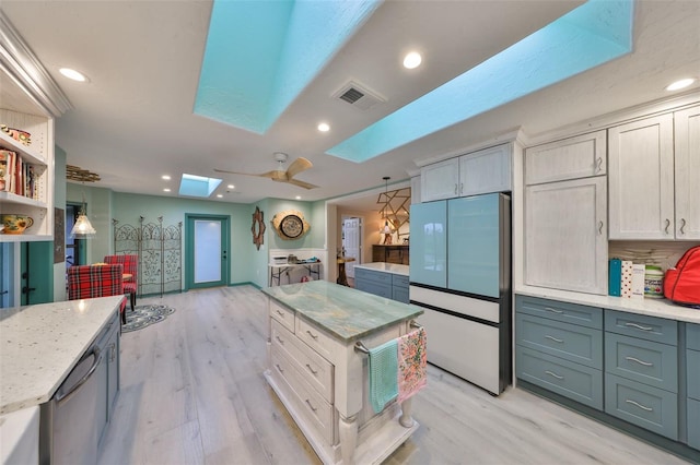 kitchen featuring recessed lighting, a skylight, visible vents, light wood-style floors, and refrigerator with glass door