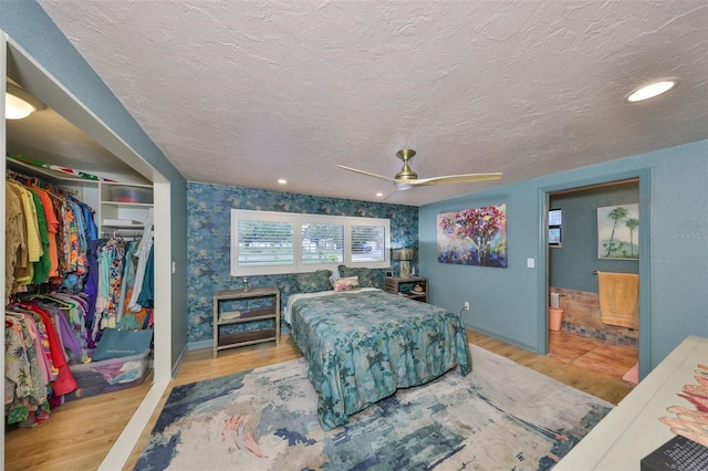 bedroom with a textured ceiling, a closet, wood finished floors, and wallpapered walls