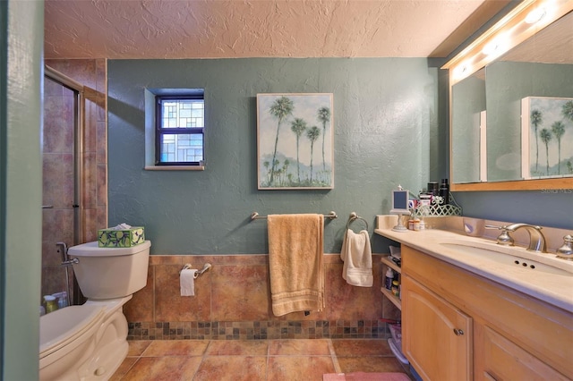 bathroom with a textured wall, toilet, vanity, a textured ceiling, and tile patterned flooring