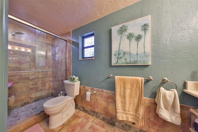 full bathroom with a textured wall, toilet, a shower stall, a textured ceiling, and tile patterned floors