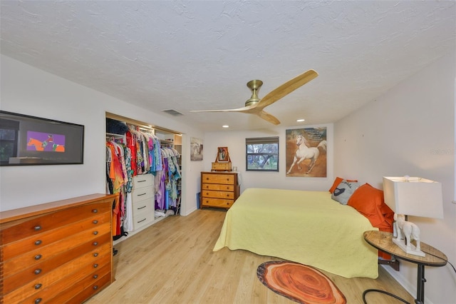 bedroom featuring visible vents, a ceiling fan, light wood-style flooring, a textured ceiling, and a closet