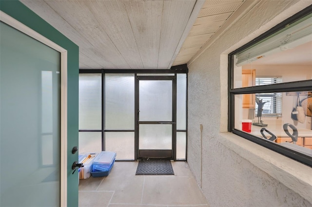 interior space with expansive windows, wooden ceiling, and a textured wall