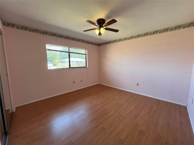 empty room featuring a ceiling fan, baseboards, and wood finished floors