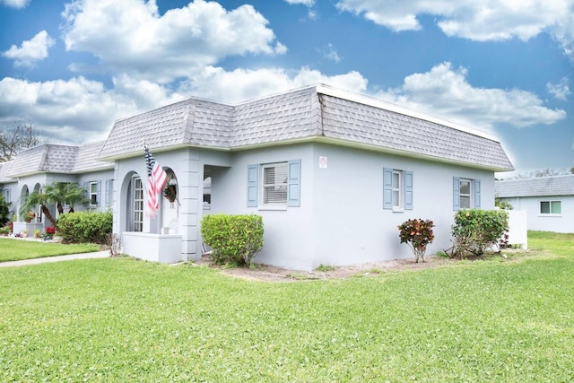 view of front of property featuring stucco siding, a front lawn, mansard roof, and roof with shingles