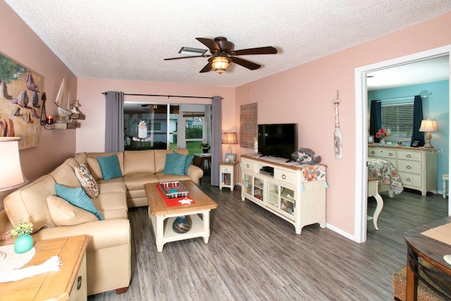 living room with a textured ceiling, ceiling fan, wood finished floors, and baseboards