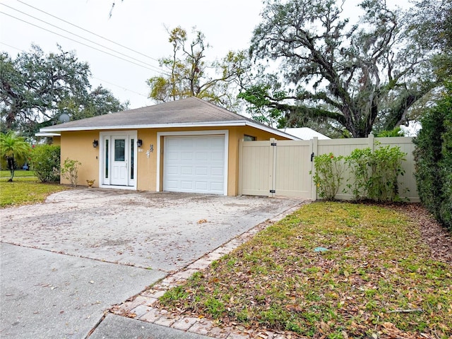 garage with driveway, a gate, and fence