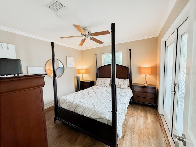 bedroom featuring ornamental molding, wood finished floors, visible vents, and baseboards