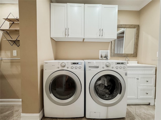 washroom with light tile patterned floors, a sink, baseboards, washer and dryer, and cabinet space