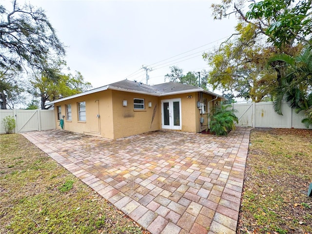 back of house featuring a patio, a fenced backyard, french doors, a gate, and stucco siding