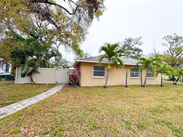 exterior space featuring a gate, a lawn, fence, and stucco siding