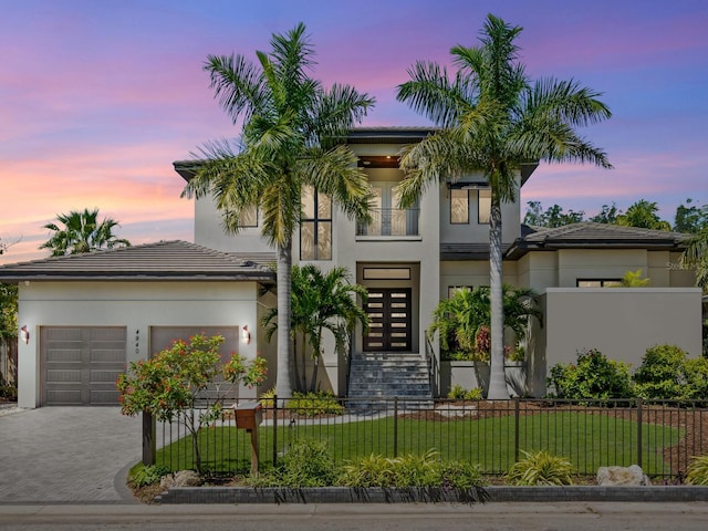 view of front of home featuring a garage, a fenced front yard, decorative driveway, a front yard, and stucco siding