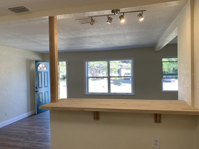 interior space featuring butcher block countertops, a breakfast bar, visible vents, and a textured ceiling