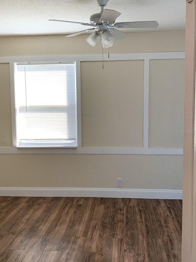 spare room featuring ceiling fan, baseboards, and dark wood-type flooring