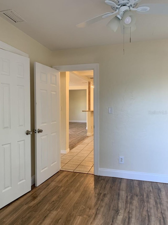 spare room with baseboards, visible vents, ceiling fan, and wood finished floors