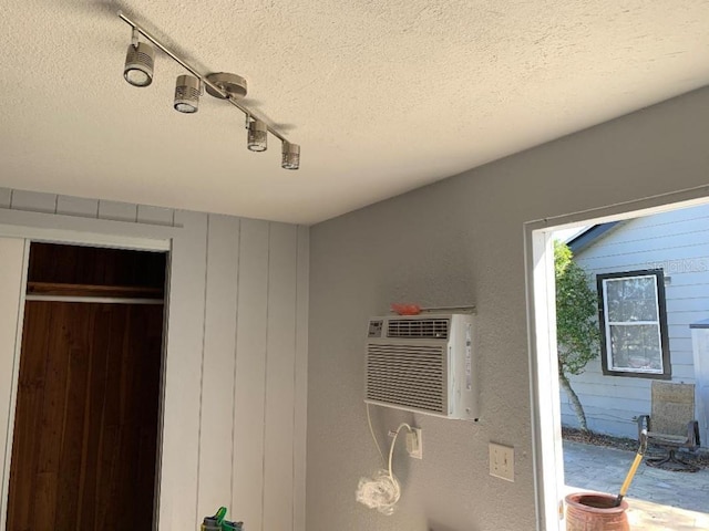 details featuring a wall unit AC, a textured ceiling, and track lighting