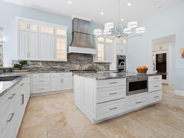 kitchen featuring premium range hood, dark stone countertops, white cabinetry, and tasteful backsplash