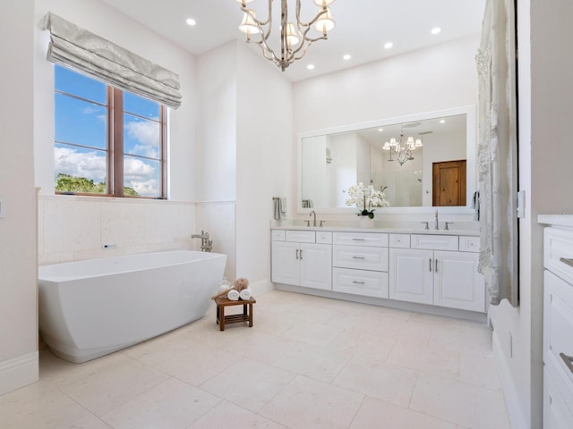 full bath with a freestanding bath, double vanity, a sink, and an inviting chandelier