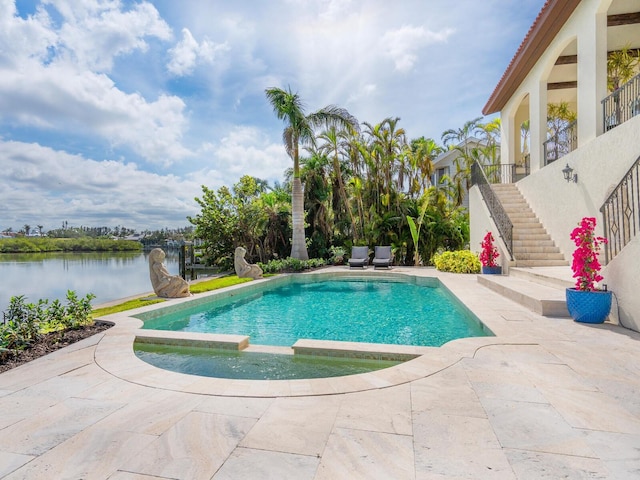 view of swimming pool featuring a pool with connected hot tub, a patio area, a water view, and stairway