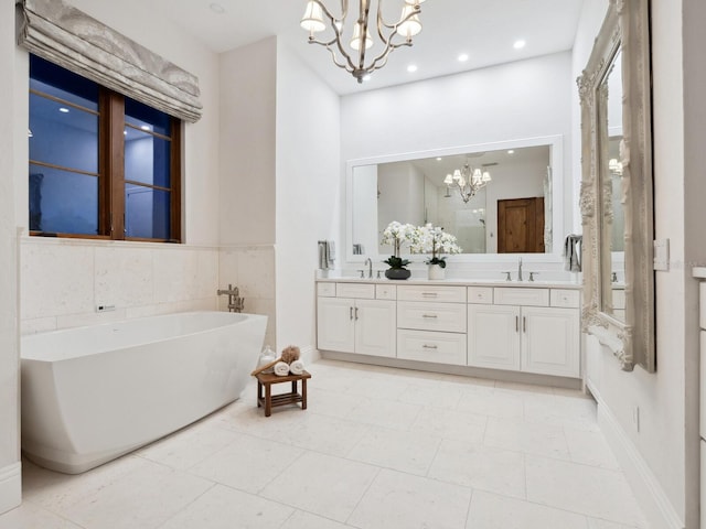 full bathroom featuring double vanity, a stall shower, a notable chandelier, a freestanding bath, and a sink