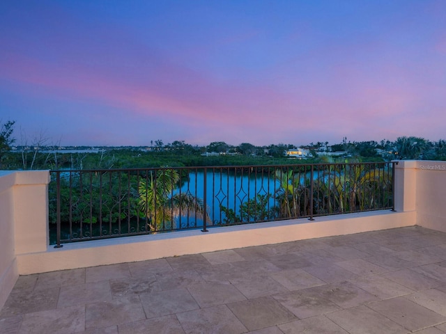 patio terrace at dusk featuring a water view