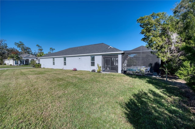 back of property featuring a lanai, a lawn, and stucco siding