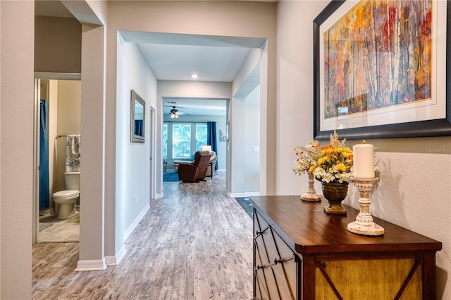 corridor featuring baseboards and wood finished floors