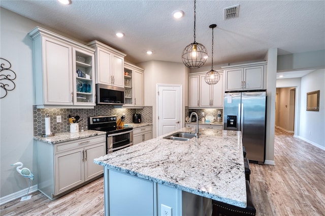 kitchen with light wood-style flooring, visible vents, stainless steel appliances, and a sink