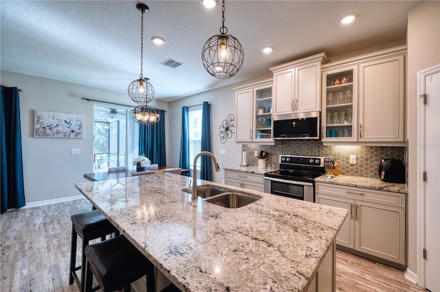 kitchen with a breakfast bar area, stainless steel appliances, a sink, visible vents, and tasteful backsplash