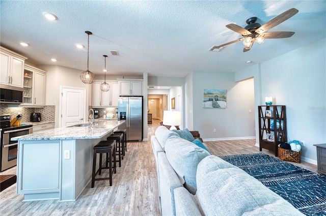 interior space with baseboards, visible vents, light wood-style flooring, and a textured ceiling