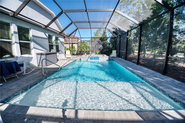 view of pool featuring a patio, glass enclosure, and a pool with connected hot tub