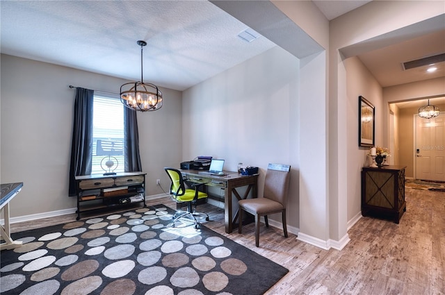 office area with baseboards, wood finished floors, visible vents, and an inviting chandelier