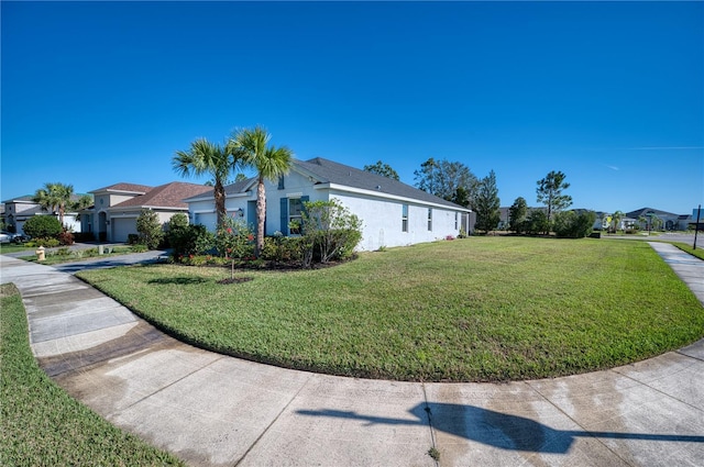 view of home's exterior with a yard, an attached garage, a residential view, and stucco siding