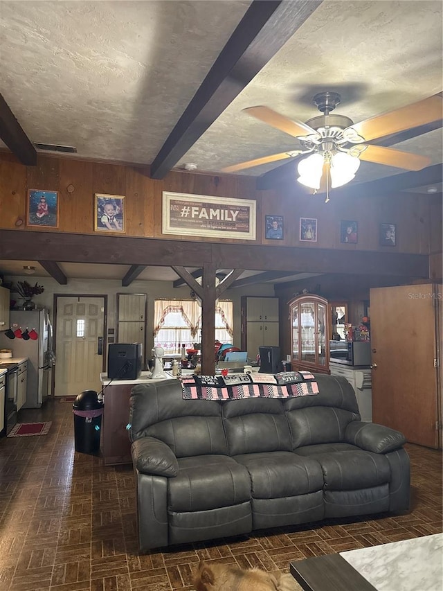 living room with visible vents, ceiling fan, beam ceiling, brick floor, and a textured ceiling