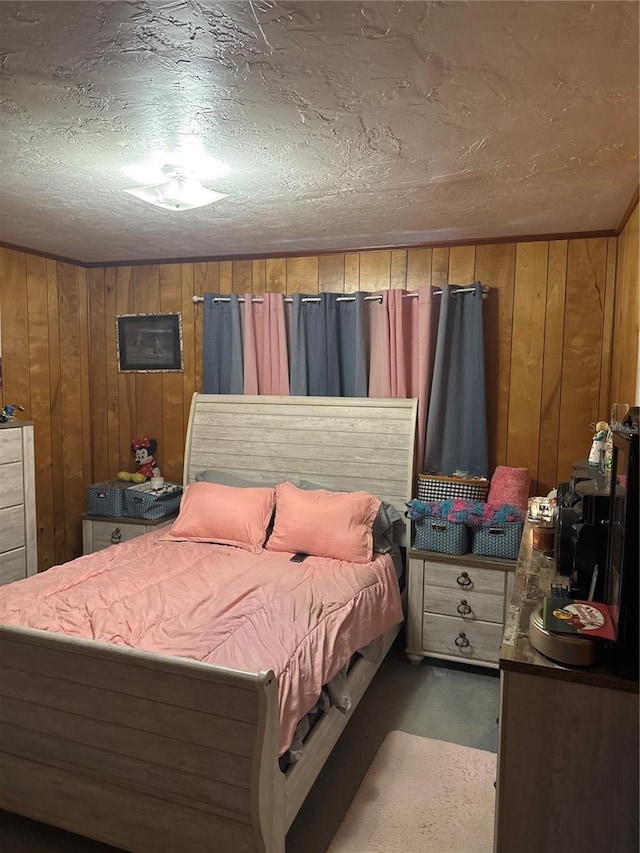 bedroom featuring wooden walls and a textured ceiling