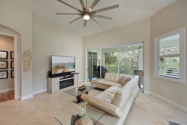 living room featuring ceiling fan, light tile patterned floors, lofted ceiling, and baseboards