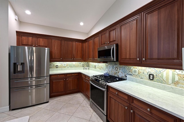 kitchen with light stone counters, light tile patterned floors, tasteful backsplash, lofted ceiling, and appliances with stainless steel finishes