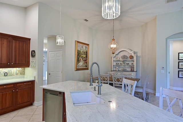 kitchen with a sink, arched walkways, dishwasher, and hanging light fixtures