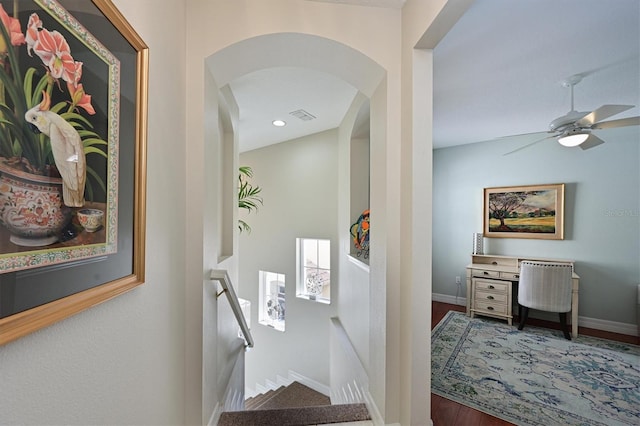 corridor featuring baseboards, wood finished floors, and an upstairs landing