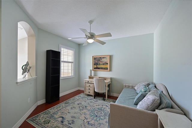 interior space with baseboards, dark wood finished floors, arched walkways, ceiling fan, and a textured ceiling