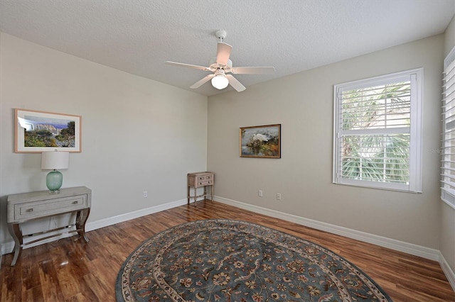 living area featuring dark wood-style floors, ceiling fan, baseboards, and a textured ceiling