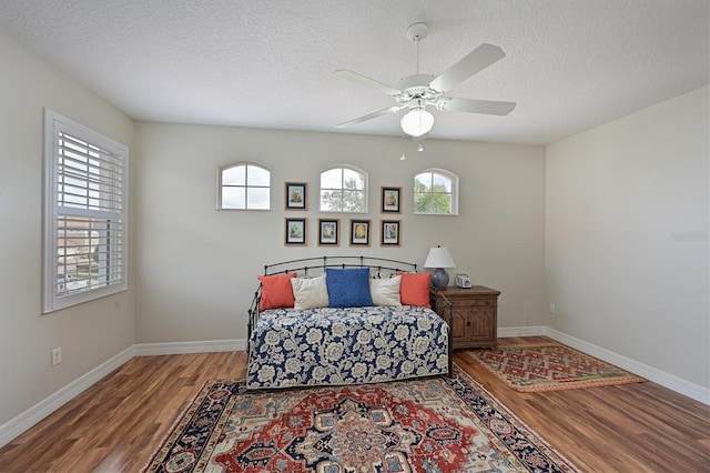 bedroom with a textured ceiling, wood finished floors, a ceiling fan, and baseboards