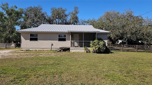 back of house featuring a sunroom, fence, metal roof, and a yard