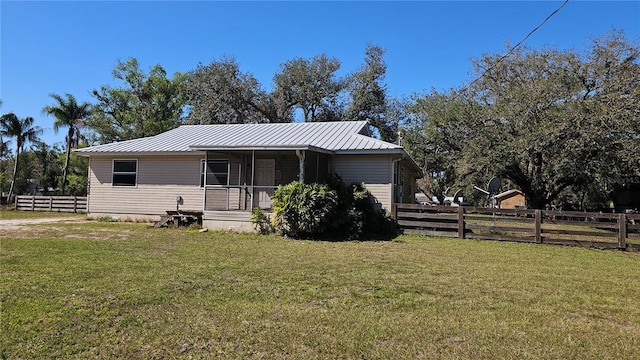 view of front of home featuring metal roof, a front lawn, and fence