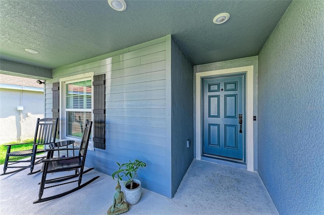 property entrance with a porch and stucco siding