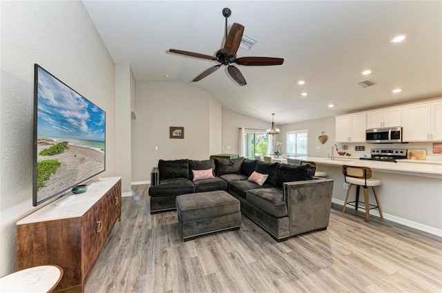 living area featuring lofted ceiling, light wood-style flooring, visible vents, and recessed lighting