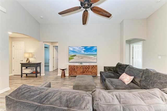 living room featuring light wood-type flooring, arched walkways, and baseboards